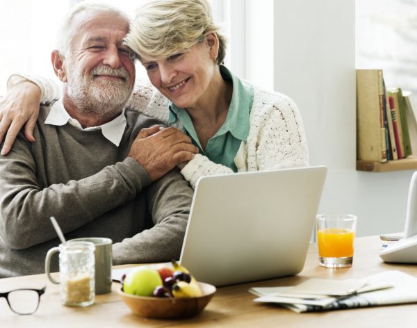 Senior couple hugging while using a laptop